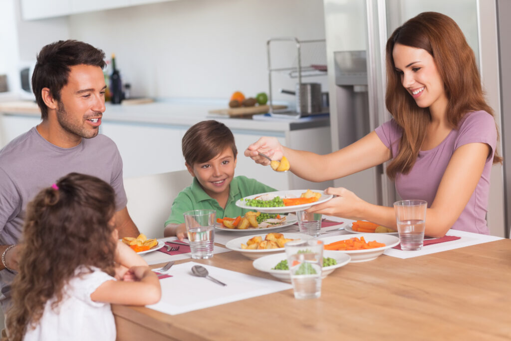 Emily and Alex, engaging in amicable co-parenting, share a cheerful family meal with their children, reflecting cooperation and care amidst mediation.